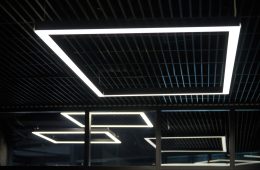 Modern office lighting. Thin lamps in office dark ceiling. LED white cold light over workplaces.